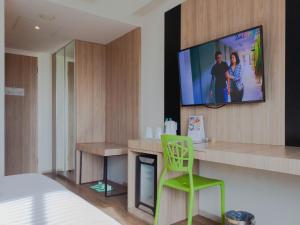 金巴兰祖里吉姆巴兰快捷旅馆的一间墙上配有电视的房间和一张绿色椅子
