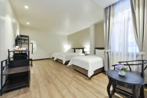 曼谷Oldthaiheng Hotel的酒店客房设有两张床和一张桌子。