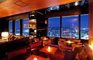 金泽金泽日航酒店的一间酒吧,配有沙发和桌子,享有城市美景