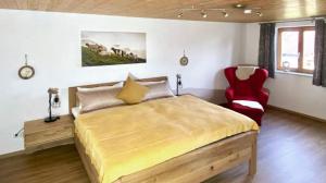 上罗伊特FeWo Apfel-Stadl, Oberreute的一间卧室配有一张大床和一张红色椅子