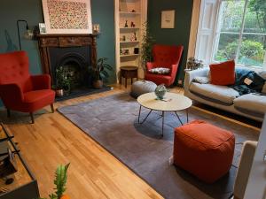 爱丁堡Large 3 double bedroom period house with parking的客厅配有红色椅子和壁炉