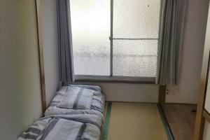 东京Little Bird Takinogawa #1的窗户前的一间房间,配有一张床