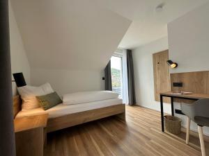 拜尔斯布龙Ferienhaus Waldschatz Baiersbronn的一间卧室配有一张带书桌的床和窗户。