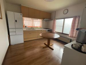 札幌辉园的厨房配有桌子和白色冰箱。