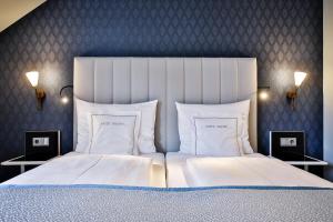 韦斯特兰Sylthotel Raffelhüschen Garni的卧室配有一张带白色床单和枕头的大床。