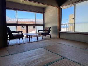 大岛素泊まり民宿とみや的一间设有两把椅子和一张桌子的房间,窗户