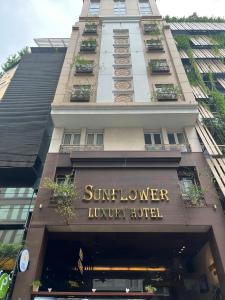 胡志明市Sunflower Luxury Hotel的一座带太阳椅的豪华酒店标志的建筑