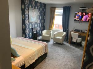 卡斯尔福德Wheldale Hotel的酒店客房配有床、椅子和电视。