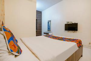 BārāmatiFabExpress Swara Residency的一间卧室配有一张床,墙上配有电视