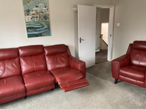 特威克纳姆Large 2-bedroom maisonette with free parking的红色真皮沙发和两把椅子