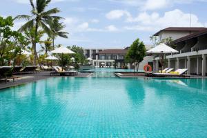 本托塔Centara Ceysands Resort & Spa Sri Lanka的度假村的游泳池配有椅子和遮阳伞