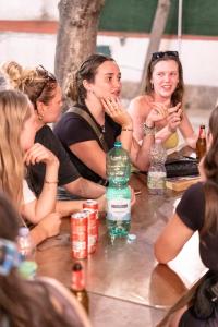 那不勒斯Naples Experience Hostel - Age Limit 18-28的一群坐在桌子旁的女士,带一瓶水