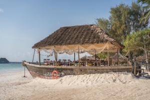 吉汶瓦吉汶瓦海滩度假酒店的茅草屋顶沙滩上的船
