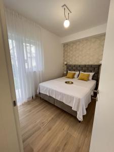 蒂瓦特DMM Apartments的一间卧室配有带白色床单和黄色枕头的床。