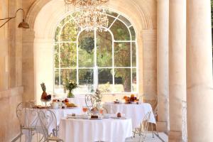 莱奥尼昂Château Léognan - Bordeaux - Nouvelle Ouverture的一间设有白色桌子和大窗户的用餐室