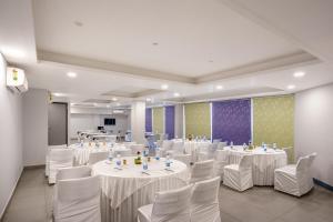 古尔冈Inde Hotel Sec- 49, Golf Course Extension, Gurgaon的宴会厅配有白色的桌子和白色的椅子