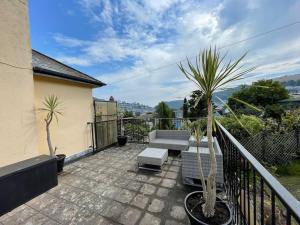 达特茅斯Elim in Dartmouth with stunning River Dart view的阳台配有庭院家具和棕榈树。