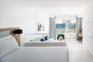 卡门港Plus Fariones Suite Hotel的一间白色的卧室,配有床和客厅