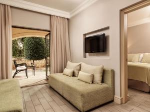 库克里亚Atlantica Aphrodite Hills Hotel的一间卧室配有一张床、一张沙发和一台电视。