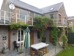 克勒伊斯贝尔亨Boskanthuisje的房屋前设有带桌子和遮阳伞的天井。