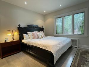 多伦多Private Suite in Forest Hill with full kitchen and parking的一间卧室设有一张大床和两个窗户。