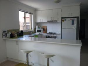 堪培拉Entire 2BR sunny house @Franklin, Canberra的厨房配有白色的柜台和白色的冰箱。