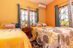 Spanish TownJ&R Sunshine Retreat的配有橙色墙壁和窗户的客房内的两张床