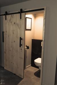 西内Le Clos du Rempart Suite & Jacuzzi的浴室设有通往卫生间的木门。
