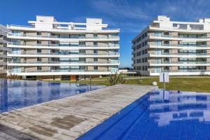 埃斯特角城Oceana Suites en Lumiere, frente a playa Mansa的一座游泳池,其两座大建筑的背景