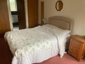 拜尔斯顿Lokiladdich的一张带白色毯子和木床头柜的床
