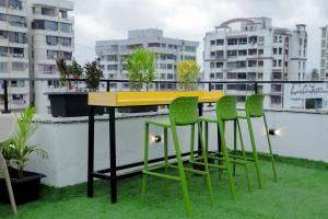 苏拉特Hotel Royal Accord的阳台设有一张黄色桌子和四把绿色椅子