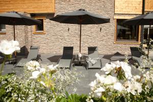 万丹斯Hotel Die Montafonerin的一个带椅子和遮阳伞及白色鲜花的庭院