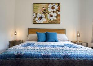 WiggintonTring Grange Cottage的一张带蓝色枕头的床和墙上的绘画