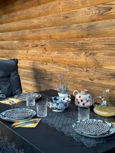 Ferienhaus_natikrausz的黑色桌子,上面有盘子和玻璃杯,花瓶
