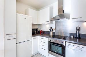 伦敦City-Close 1-Bed Apartment near Tower Hill的厨房配有白色橱柜和炉灶烤箱。