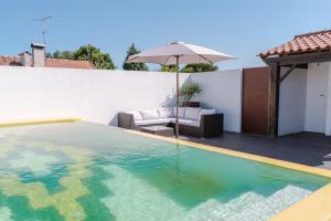 Retiro da Atafona Beach Pool House White的一座房子旁带遮阳伞的游泳池