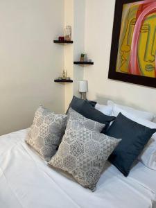 卡拉尔卡Apartamento cacique calarca的一张带枕头的白色床和墙上的绘画