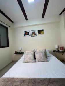 卡拉尔卡Apartamento cacique calarca的卧室配有一张带两个枕头的大白色床