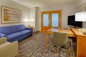 罗斯芒特Embassy Suites by Hilton Chicago O'Hare Rosemont的客厅配有蓝色的沙发和带电脑的书桌