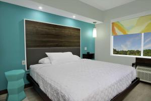 布赖恩Tru by Hilton Bryan College Station的卧室配有白色的床和蓝色的墙壁