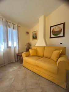 奥尔比亚Venti di Vacanza - Levante & Grecale的客厅里一张黄色的沙发,配有桌子