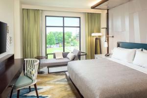 夏洛特Canopy By Hilton Charlotte SouthPark的酒店的客房 - 带一张床、椅子和窗户