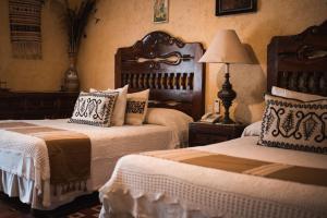 Portes GilHacienda El Carmen Hotel & Spa的一间卧室配有两张床和一张带台灯的桌子