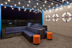 奥本Tru by Hilton Auburn的休息区配有蓝色的沙发和橙色的凳子。