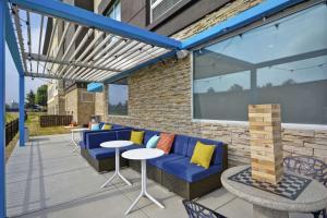 费尔伯恩Tru By Hilton Beavercreek Dayton的庭院设有蓝色的沙发和桌椅。