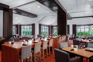迪尔菲尔德海滩迪尔菲尔德海滩博卡拉顿希尔顿逸林酒店的餐厅设有木桌、椅子和窗户。