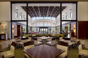 罗缪勒斯Embassy Suites by Hilton Detroit Metro Airport的餐厅设有桌椅和大窗户。