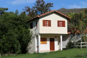 圣托梅-达斯莱特拉斯Chalé e Camping Elementais的白色的房子,设有棕色的窗户和栅栏