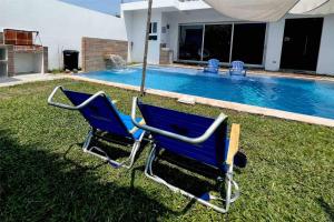 TaxiscoLas Villas Taxisco的两把蓝色椅子坐在游泳池附近的草地上