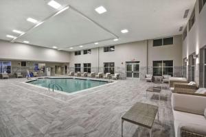 沃伦Homewood Suites By Hilton Warren Detroit的一个带桌椅的大房间中间的游泳池